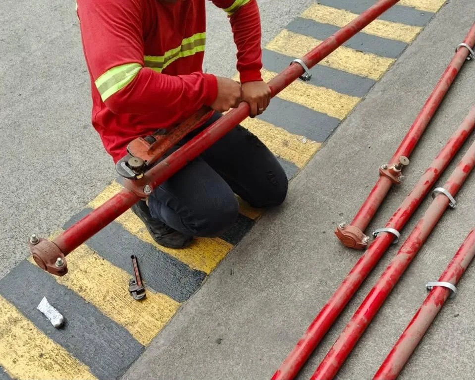 Técnico conectando tuberías CI rojas en obra